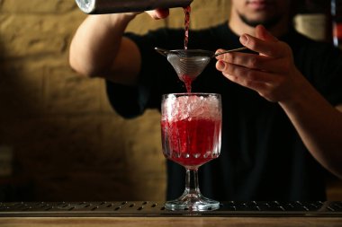 Barmen tezgahta taze alkollü kokteyl hazırlıyor.