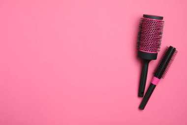 Pembe arka planda modern yuvarlak saç fırçaları, düz yatış. Metin için boşluk