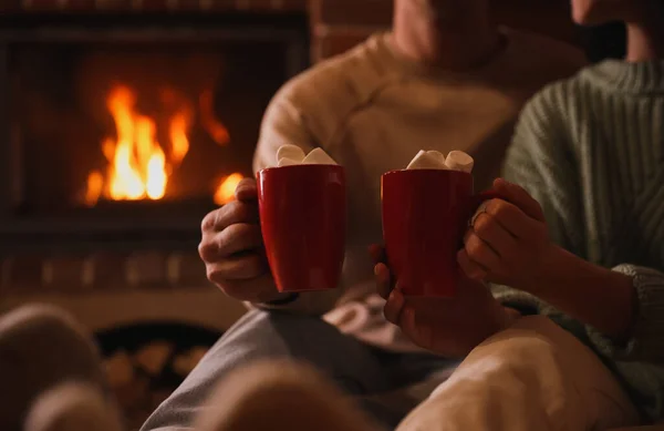 Lovely couple with sweet cocoa near fireplace indoors, closeup