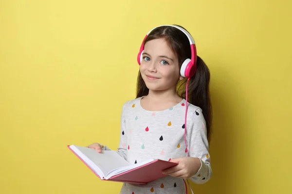 Cute Little Girl Słuchawkami Słuchając Audiobook Żółtym Tle — Zdjęcie stockowe