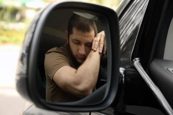 坐着汽车在方向盘上睡觉的疲倦的人 从汽车侧面的镜子看 — 图库照片