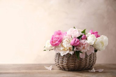 Hasır sepetin içinde ahşap masanın üzerinde güzel şakayık buketi. Metin için boşluk