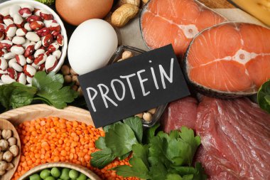 Kelime PROTEIN ve arkaplan olarak farklı ürünler içeren kart, düz yatıyordu