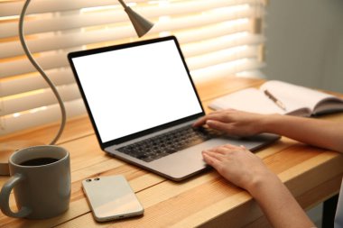 Ahşap masada modern dizüstü bilgisayarla çalışan bir kadın, yakın plan. Tasarım için boşluk