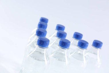 Beyaz arka planda saf su bulunan plastik şişeler, yakın plan.