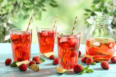 Açık mavi ahşap masada çilekli ve limonlu içecek.