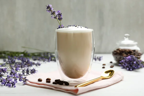 Delicious coffee with lavender and beans on white wooden table