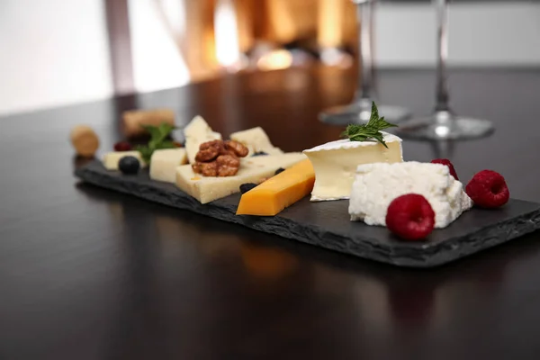 Different types of delicious cheeses with berries and nuts on table