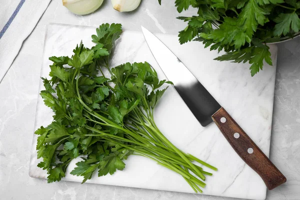 テーブルの上に新鮮な緑のパセリとナイフで大理石のボード フラットレイアウト — ストック写真