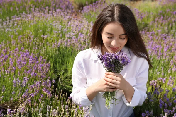 Young woman with lavender bouquet in field on summer day