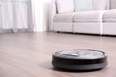 Modern robot elektrikli süpürgeyle yerleri süpürüyor. Metin için boşluk