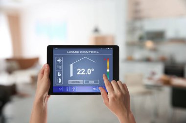 Kapalı alan sıcaklığını ayarlamak için tablet kullanan kadın, yakın çekim. Akıllı ev otomasyon sistemi