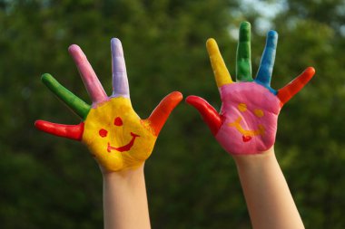 Yeşil parktaki avuç içlerine gülümseyen çocuk, yakın plan.