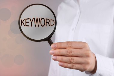 Kadın büyüteçle anahtar kelimeyi gösteriyor, yakın plan.