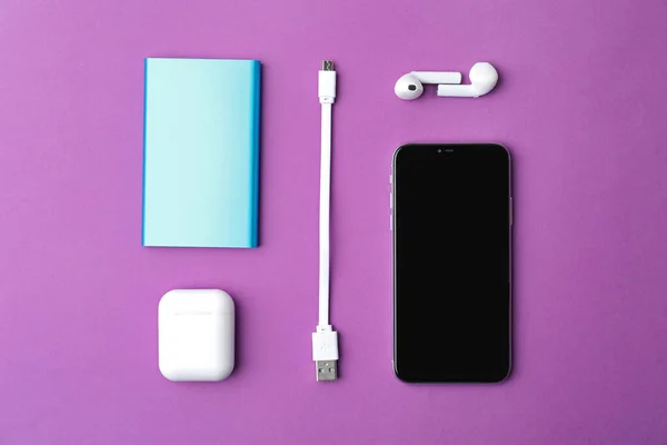 USB charge cable and gadgets on purple background, flat lay