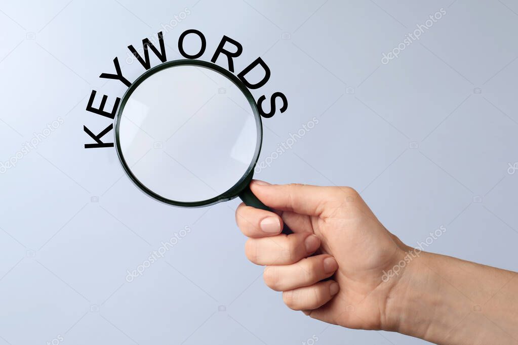 Woman holding magnifying glass with word keyword, closeup