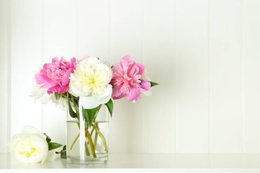 Beyaz masadaki vazoda bir buket güzel şakayık. Metin için boşluk