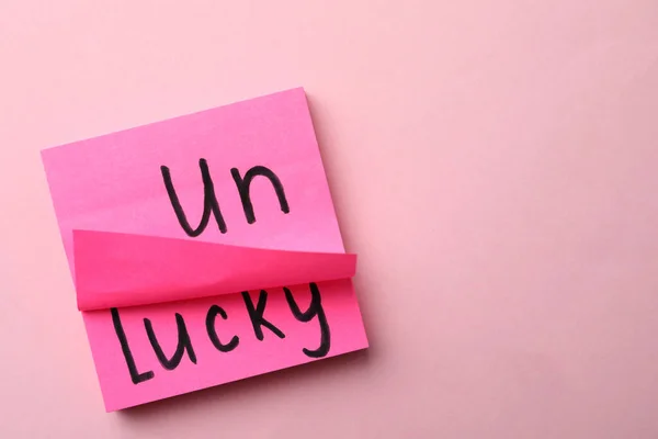 带有粉红背景的单词Unlucky的笔记 顶部视图 案文的篇幅 — 图库照片