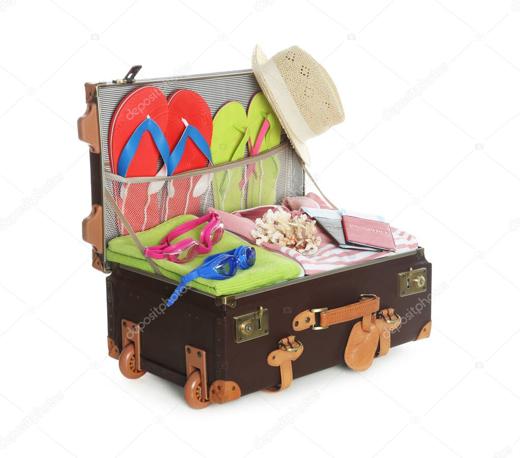 Open vintage suitcase with different beach objects packed for summer vacation isolated on white