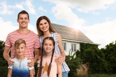 Evlerinin yakınında güneş panelleri olan mutlu bir aile. Alternatif enerji kaynağı