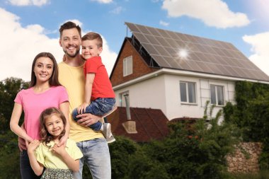 Evlerinin yakınında güneş panelleri olan mutlu bir aile. Alternatif enerji kaynağı