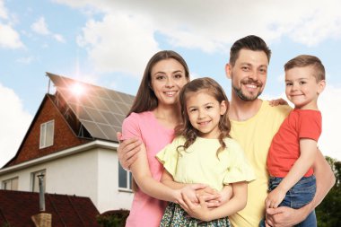 Evlerinin yakınında güneş panelleri olan mutlu bir aile. Alternatif enerji kaynağı