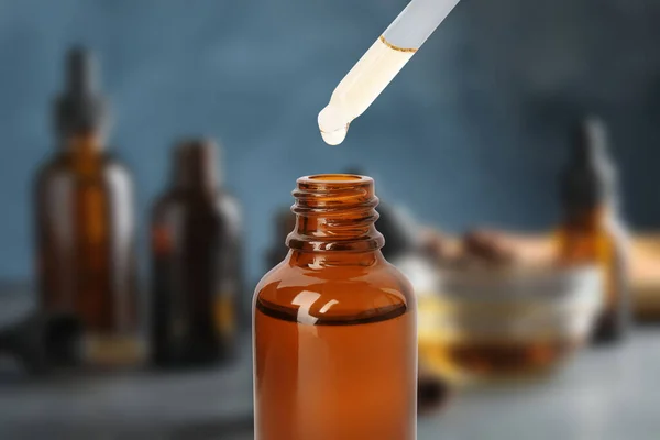 Little bottle with essential oil and dropper against blurred background