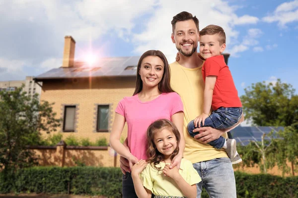 Happy family near their house with solar panels. Alternative energy source