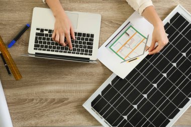 Ahşap masadaki güneş panelleriyle ev projesinde çalışan mimar. Alternatif enerji kaynağı
