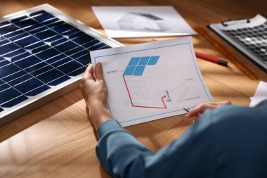 Ofiste güneş panelleri olan ev projesinde çalışan bir kadın, yakın plan.