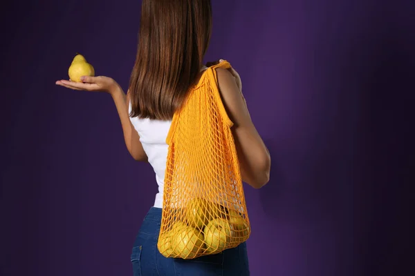 紫の背景に新鮮な熟した梨と女性がネットバッグを保持 クローズアップ — ストック写真