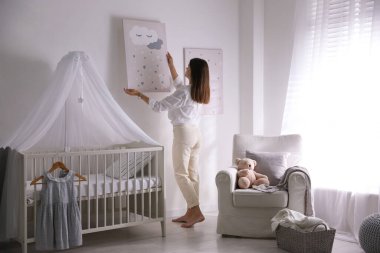 Çocuk odasının duvarına resim asan bir dekoratör. İç tasarım