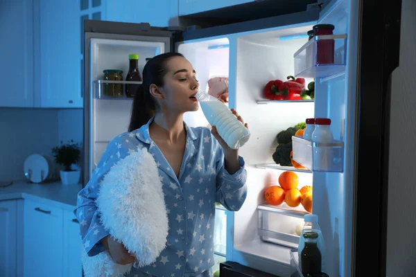 Молодая Женщина Подушкой Пьет Молоко Возле Открытого Холодильника Ночью — стоковое фото