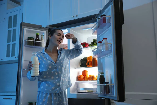 Молодая Женщина Бутылкой Молока Возле Открытого Холодильника Ночью — стоковое фото