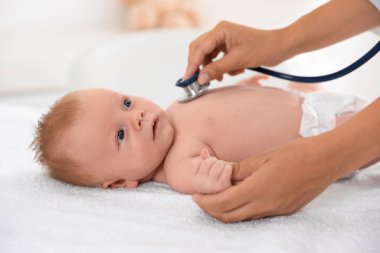 Doktor, şirin bebeği steteskopla muayene ediyor, yakın plan. Sağlık hizmetleri