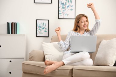 Evde kanepede oturan laptoplu duygusal genç kadın.