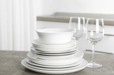 Mutfaktaki mermer masada bir yığın temiz tabak ve bardaklar.