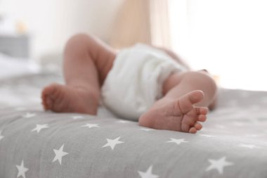 Bebek bezli şirin bir bebek yatakta uzanıyor, yakın plan.