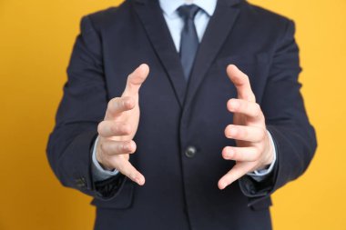 Turuncu arka planda bir şey tutan işadamı, ellerine odaklan.