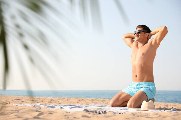 Happy man with slim body resting on beach. Space for text