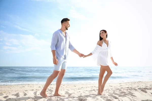 快乐的年轻夫妇手牵手在海滩上 — 图库照片