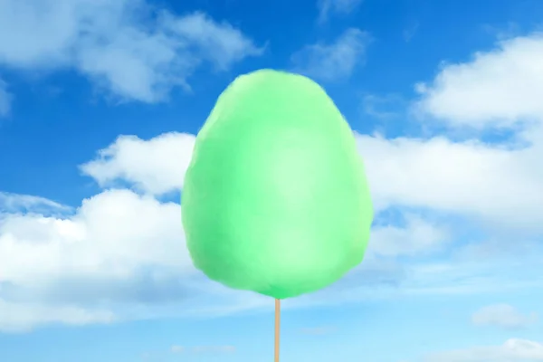 Green cotton candy against blue sky with clouds