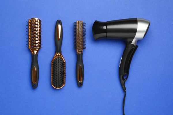 头发烘干机和不同的刷子在蓝色的背景上 平坦平整 专业理发师工具 — 图库照片