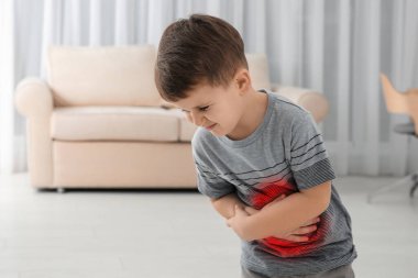 Küçük çocuk oturma odasında mide ağrısı çekiyor.