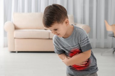 Little boy suffering from stomach pain in living room clipart
