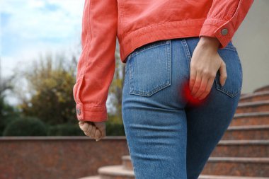 Woman suffering from hemorrhoid outdoors, closeup view clipart