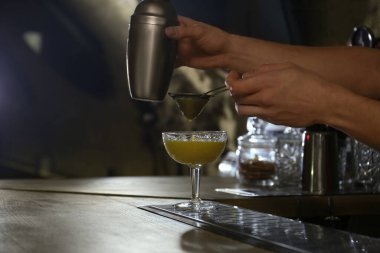 Barmen tezgahta taze alkollü kokteyl hazırlıyor.