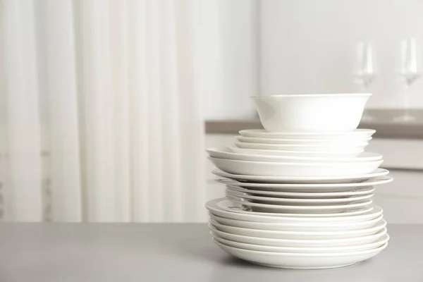 Stack of clean plates on grey table in kitchen. Space for text