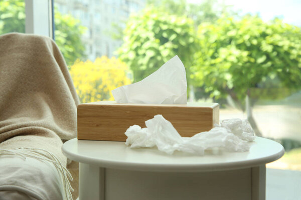 Бумажные салфетки и деревянный держатель на белом столе