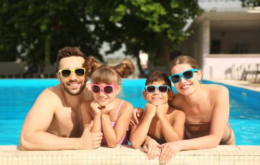 Güneşli bir günde havuzda mutlu bir aile.